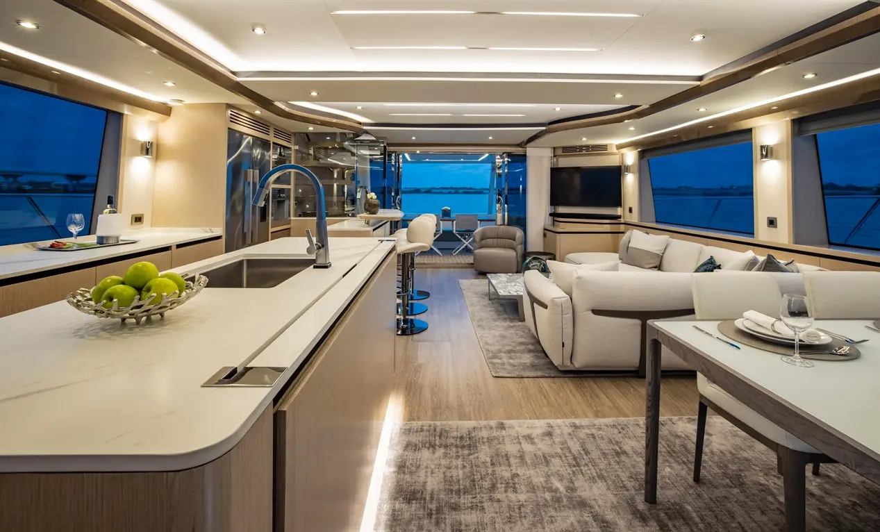Modern yacht interior featuring a sleek kitchen, living area, and spacious windows with a sunset view.